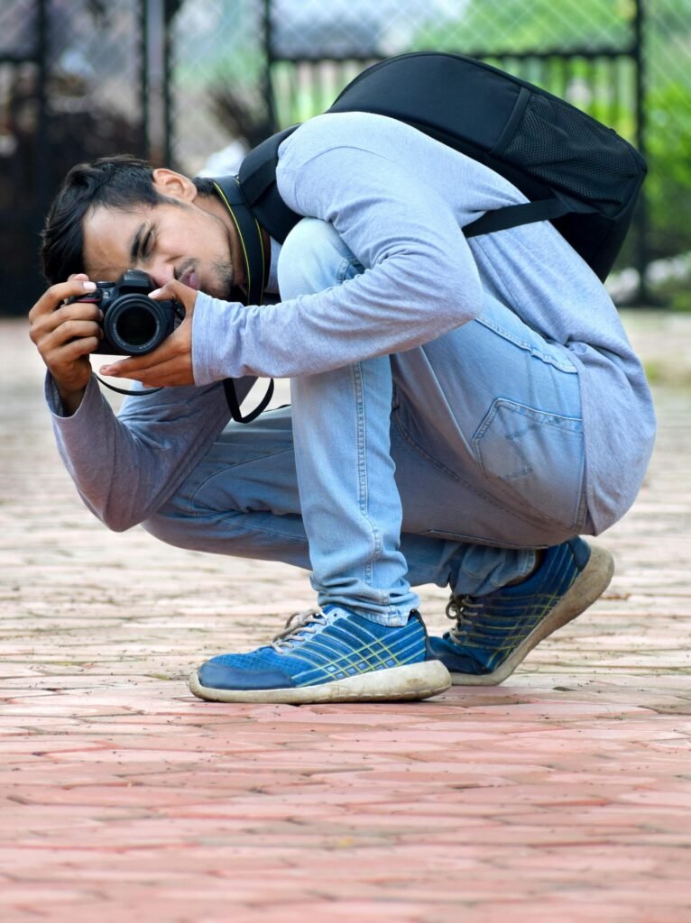 A man crouching down with a camera and backpack